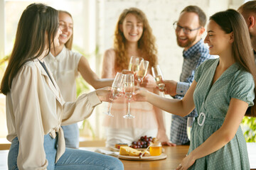 Team. People clinking glasses with wine or champagne. Happy cheerful friends celebrate holidays, meeting. Close up shot of smiling friends, lifestyle. Party at home or in restaurant, cafe.