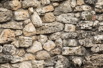 background of the antique wall of the old stone. Weathered surface. Stones of different sizes and shapes