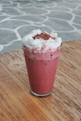 Close up of iced red velvet latte on top of a wooden table.