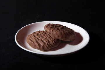Top view of biscuits. Two biscuits, white plate, black background
