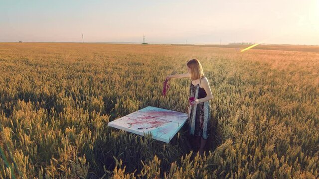 female artist who paints a picture in the field with ears of wheat.