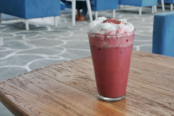 Close up of iced red velvet latte on top of a wooden table.