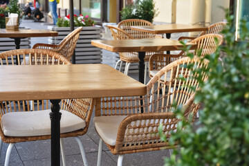 wooden tables and wicker chairs in a cafe on the street without visitors