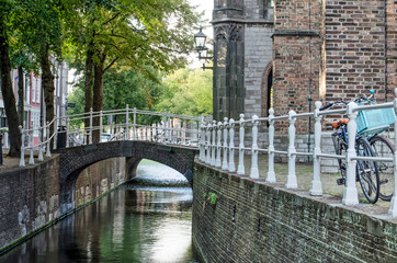 Delft, The Netherlands, August 23, 2020: the narrowest section of Oude Delft canal next to the tower of the Old Church