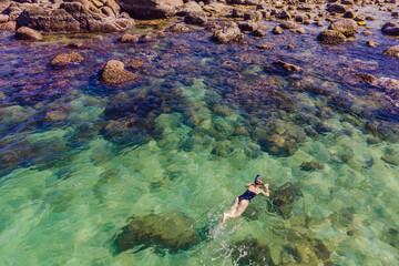 The woman is snorkeling among the corals. View from the drone