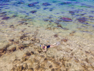 Fototapeta na wymiar The woman is snorkeling among the corals. View from the drone