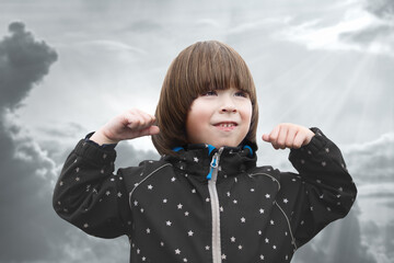 Boy is showing power sign at cloudy background