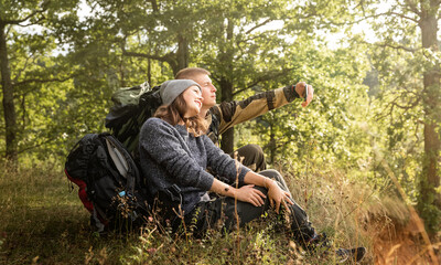 A young girl and her boyfriend are sitting on the Bank of a river and taking selfies.