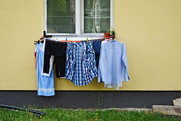 Wet clothes hanging on wire to dry in front of an old window