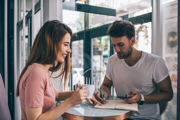 Obraz premium Happy young couple of students sitting at table in cafe