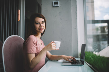 Smiling female drinking coffee during remote work