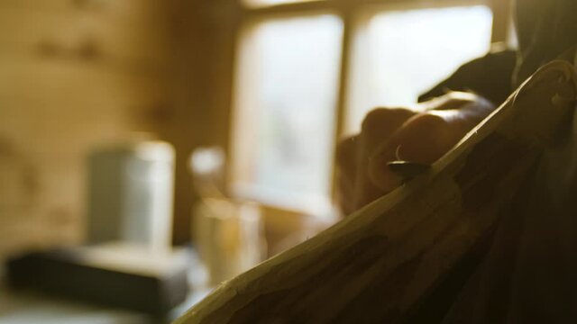 Male hand carving into a piece of wood close up with incense burning in the background	