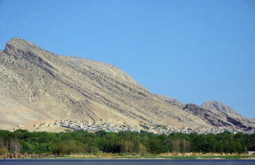 A village in the Fars province, Iran, at the foot of a rocky mountain.