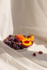 juicy fresh peaches and grapes on a plate on a light background