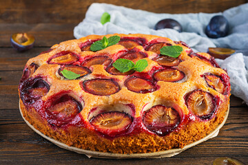 Delicious homemade plum pie on rustic background