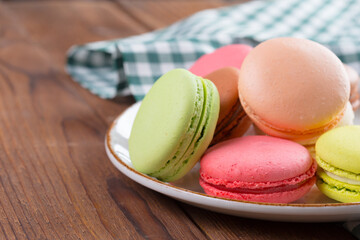 Colorful macaroon cookies on white plate close up