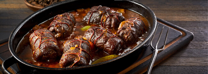 Oven dish with serving of roulades in spicy gravy