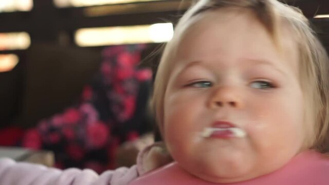 Close up of one year old chubby baby girl fed from spoon open mouth very wide funny happy child