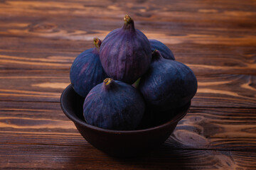 Tasty figs in a bowl on wooden background. Top view.