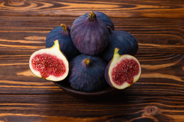 Tasty figs in a bowl on wooden background. Top view.