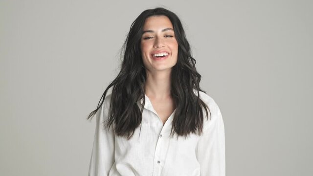 A beautiful young woman is smiling standing isolated over gray background