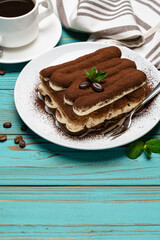 portion of Classic tiramisu dessert, cup of coffee and milk or cream on wooden background
