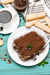 portion of Classic tiramisu dessert, cup of coffee and savoiardi cookies on wooden background