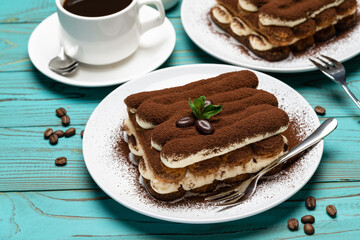 Two portions of Classic tiramisu dessert, cup of coffee and milk or cream on colorful blue wooden background