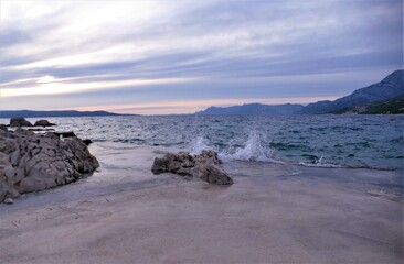 Fototapeta na wymiar Purple sunset and big rock on th coastline