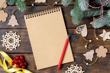 Happy New Year and merry Christmas. Wooden ornaments on the branches of the Christmas tree. Christmas background with an open Notepad. Concept of a Santa Claus letter or gift list