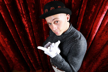 Young caucasian man in black bowler hat  with funny face and white gloves posing like master of...