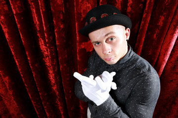 Young caucasian man in black bowler hat  with funny face and white gloves posing like master of...