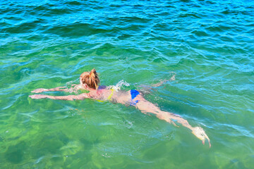 A young woman floats on the sea on a sunny summer day.