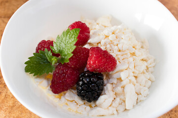 Healthy morning breakfast. Fresh cottage cheese with raspberries, blackberries and a mint leaf in a white plate close-up. Protein breakfast option for weight loss and weight loss.