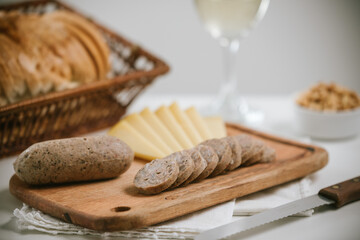 Queso de cerdo codeguín en tabla de madera con quesos y pan, acompañado de vino blanco
