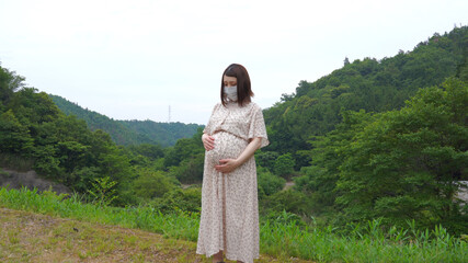 マスク姿でお腹を撫でる妊婦さん