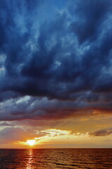 Dramatic sunset over the sea with dark storm clouds and glowing sky. Vivid colors and natural contrast create a powerful seascape atmosphere