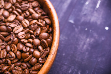 Dark Coffee Beans in a wood Cup. Symbolic image. Rustic wooden background. Close up. Copy space.