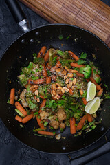 Vegan carrot, broccoli and cauliflower stir fry with nuts and seeds, black wok