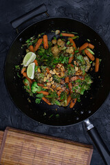 Vegan carrot, broccoli and cauliflower stir fry with nuts and seeds, black wok