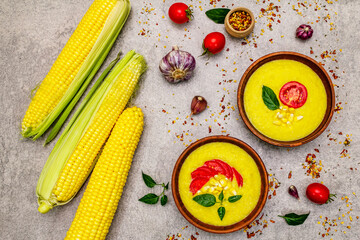 Fototapeta na wymiar Corn cream soup with fresh vegetables, herbs and spices