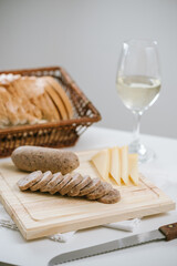Queso de cerdo codeguín en tabla de madera con quesos y pan, acompañado de vino blanco