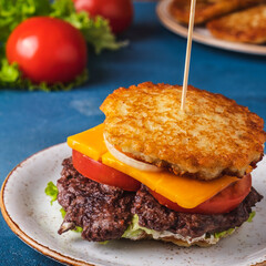 Potato pancakes burger with meat, tomatoes, onion, cheese and sauce. Dranburger