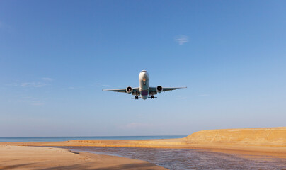 Commercial airplane landing above sea in summer season and clear blue sky over beautiful scenery nature background,concept business travel and transportation background.