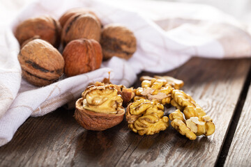 Walnut kernels and whole walnuts on rustic old wooden table. Fresh walnuts on wooden board.
