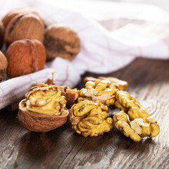Walnut kernels and whole walnuts on rustic old wooden table. Fresh walnuts on wooden board.