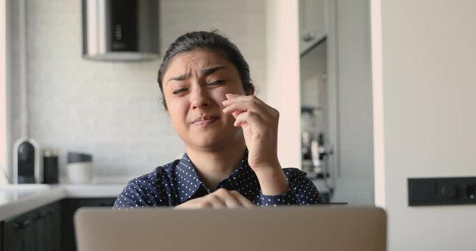 Tired after long usage of computer indian woman takes off glasses rub nose bridge reduces painful feelings rest sit at workplace. Overworked person, need vision correction, break from device concept