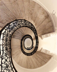 Gray round spiral staircase with black railings with patterns down view