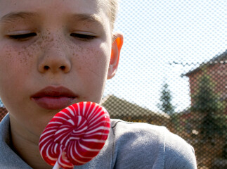The boy is eating a delicious lollipop. The boy is eating a delicious lollipop. The boy licks the...