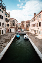 Narrow canal with boats in Venice Italy